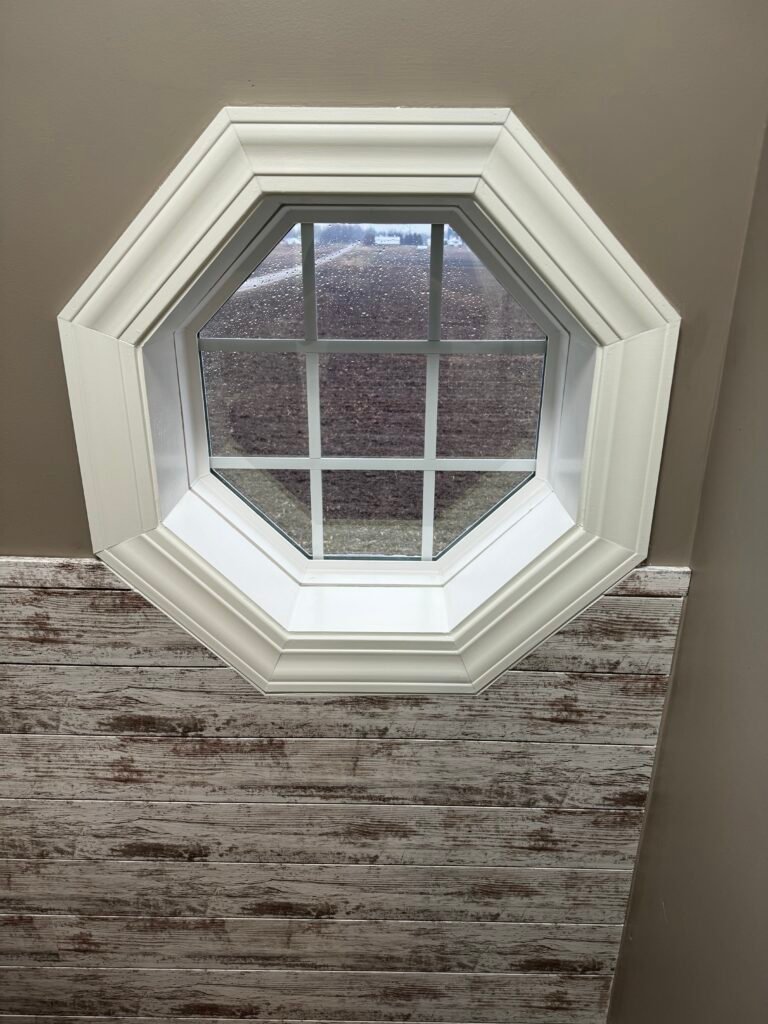 New white-painted trim around an octagon window during an interior restoration