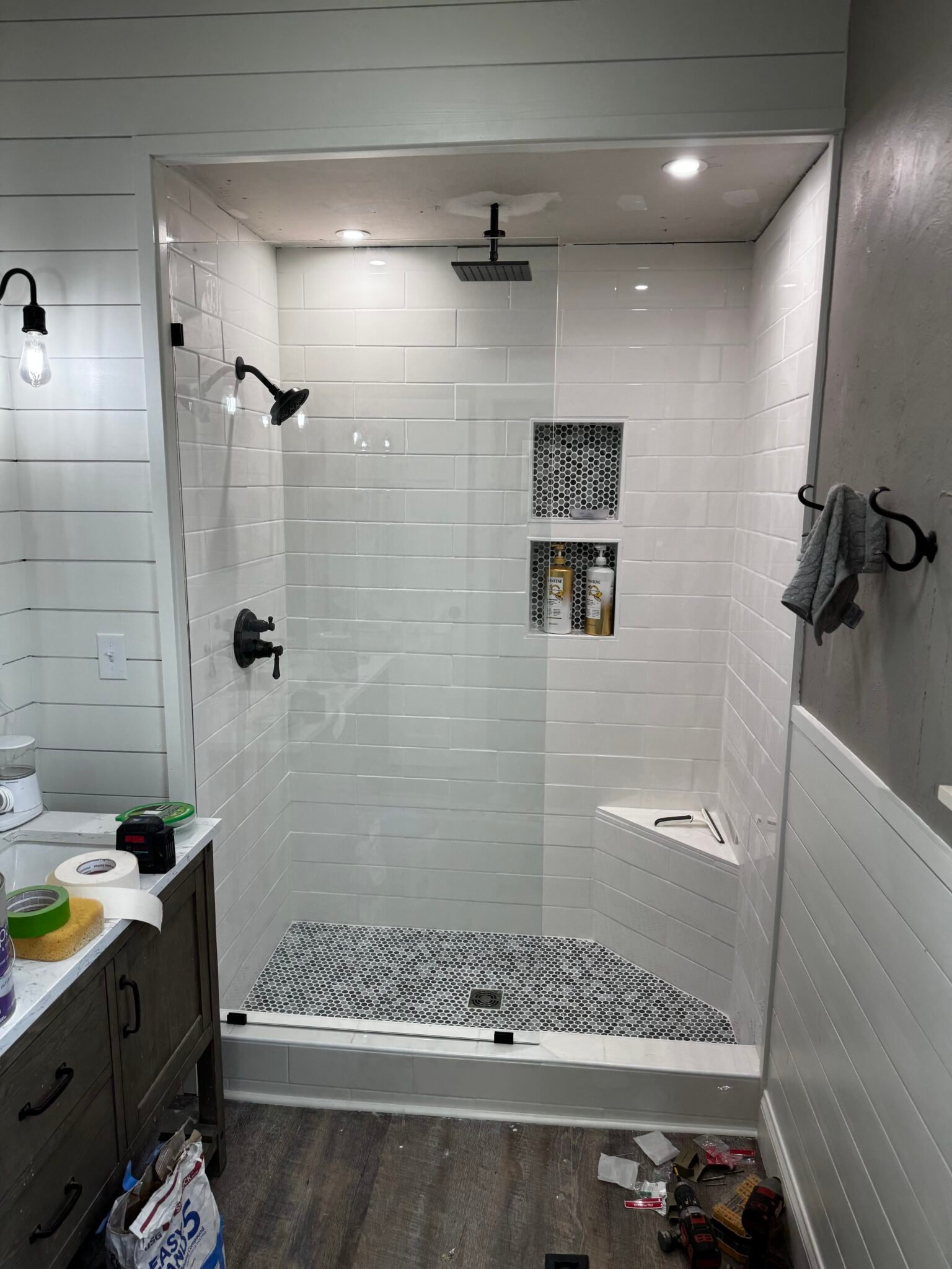 Remodeled bathroom with frameless glass shower, tile surround, and mosaic floor inset