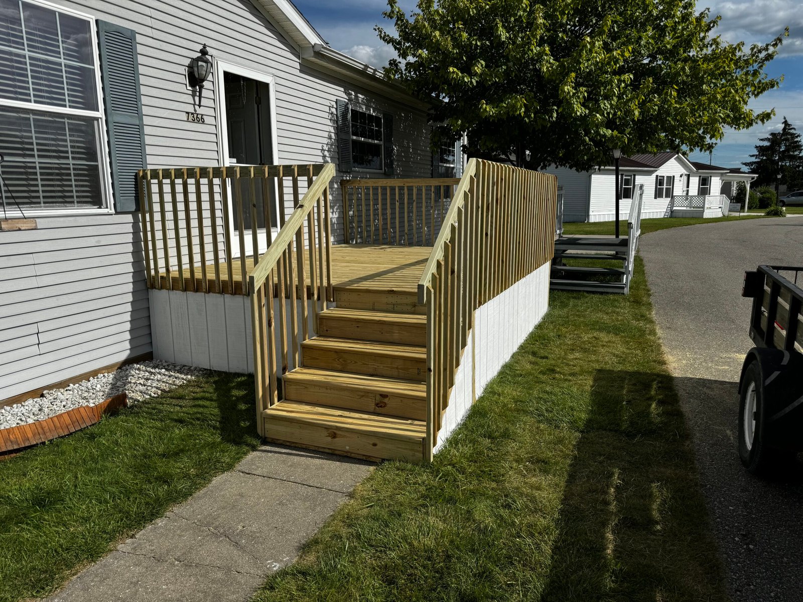 New deck stairs with white vinyl railing at a manufactured home entrance
