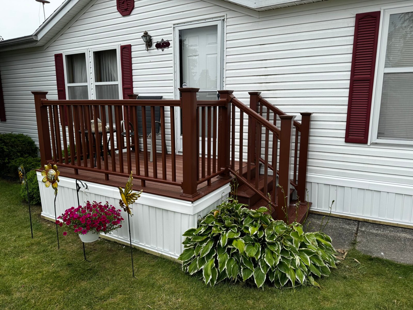 Reddish-brown stained wood deck with white railing and flower boxes