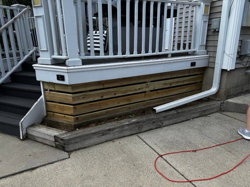 Rebuilt front porch steps with white railing and new downspout