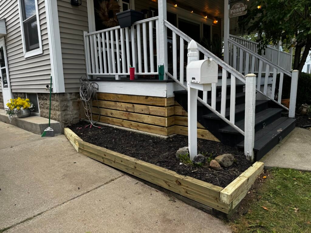 Small covered entry porch with new wood steps, white columns, and railing