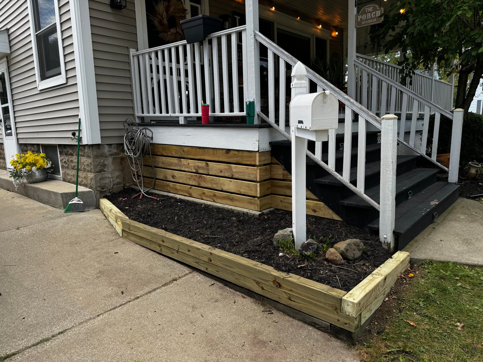 Small covered entry porch with new wood steps, white columns, and railing
