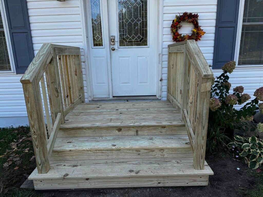 Covered wood entry steps with white handrail leading to the front door