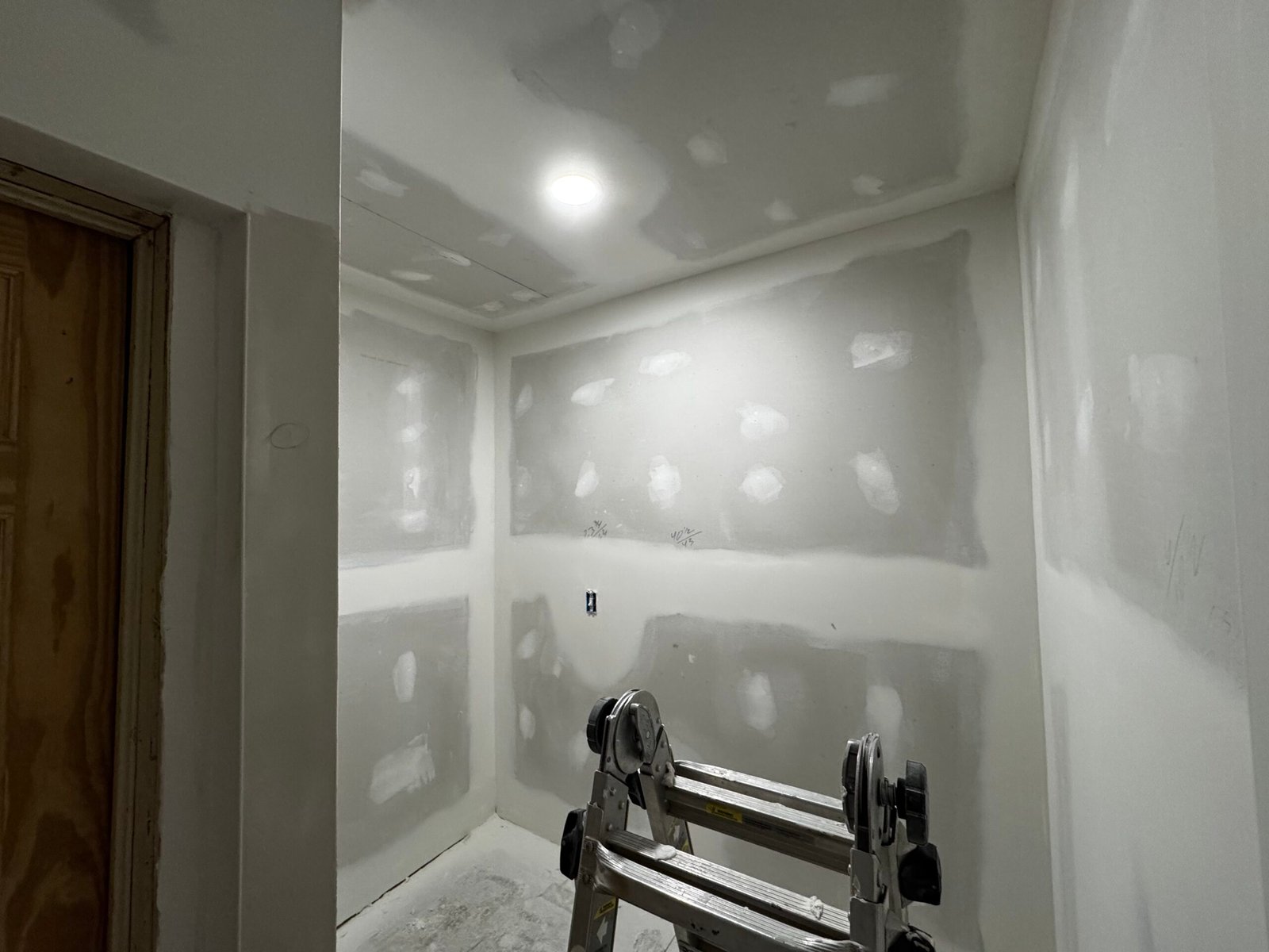Freshly hung and taped drywall in a small room, ready for finishing
