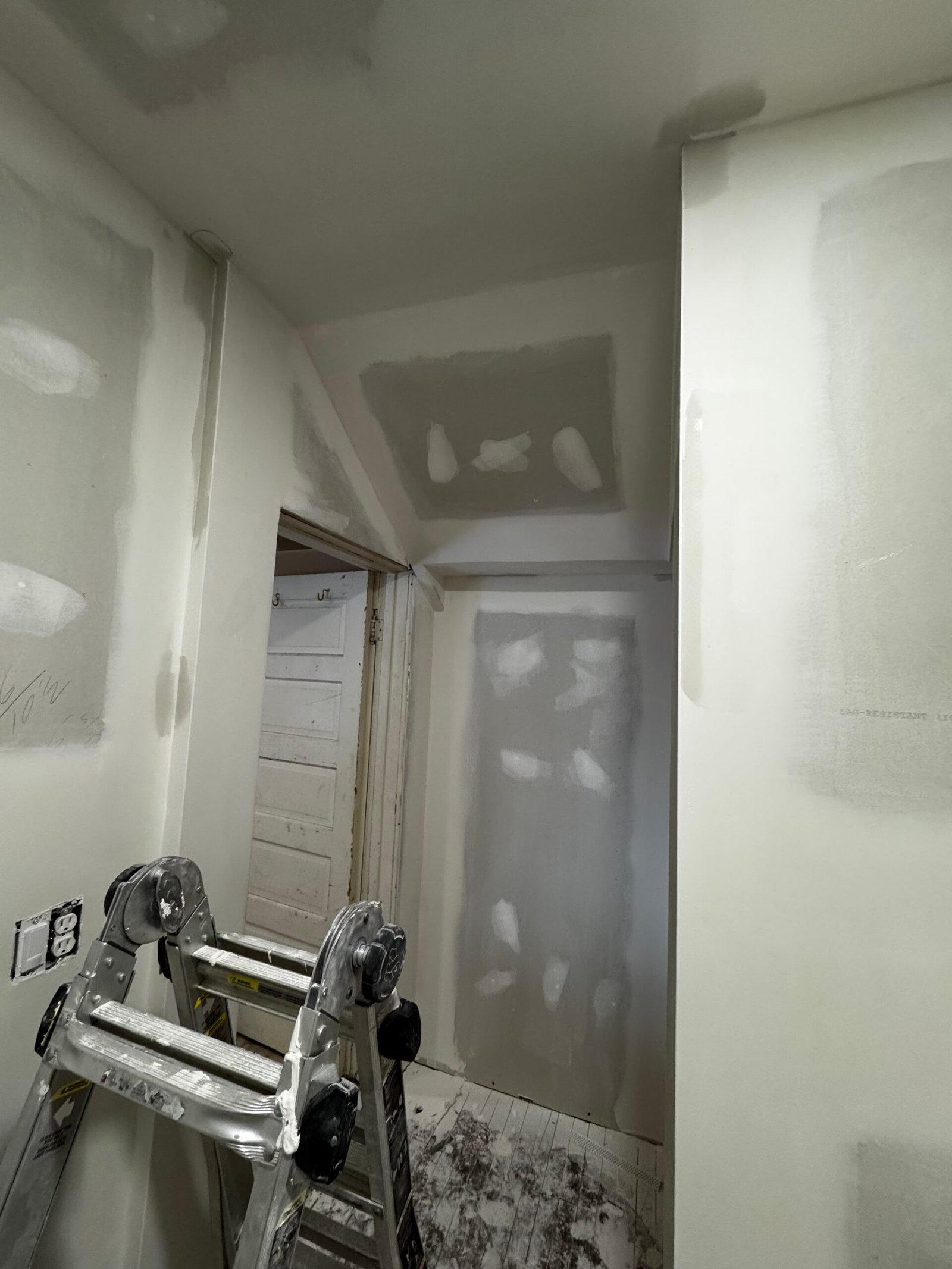 Drywall mudding and sanding in progress in a hallway