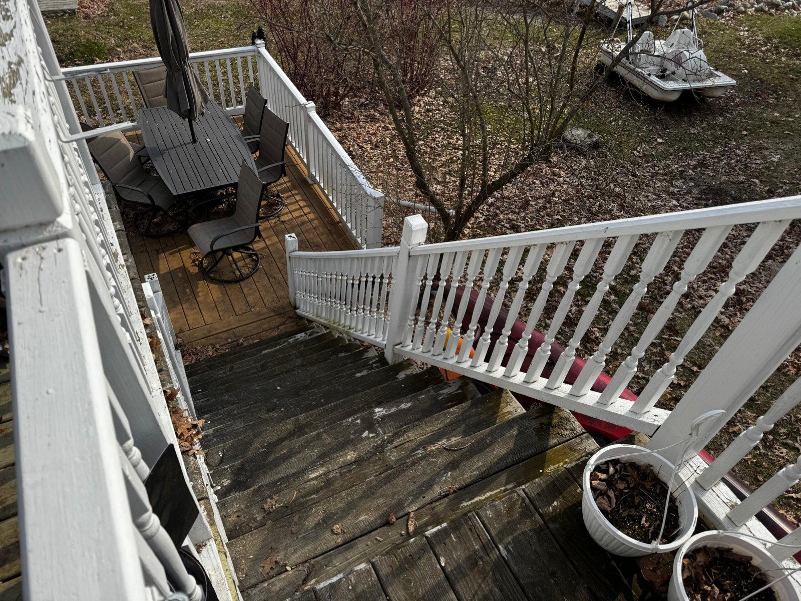 Wood deck and stairway finished with white railings in a wooded backyard