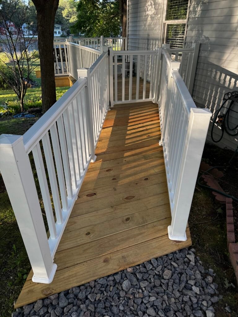 Wood accessibility ramp with white railing leading to a home entrance