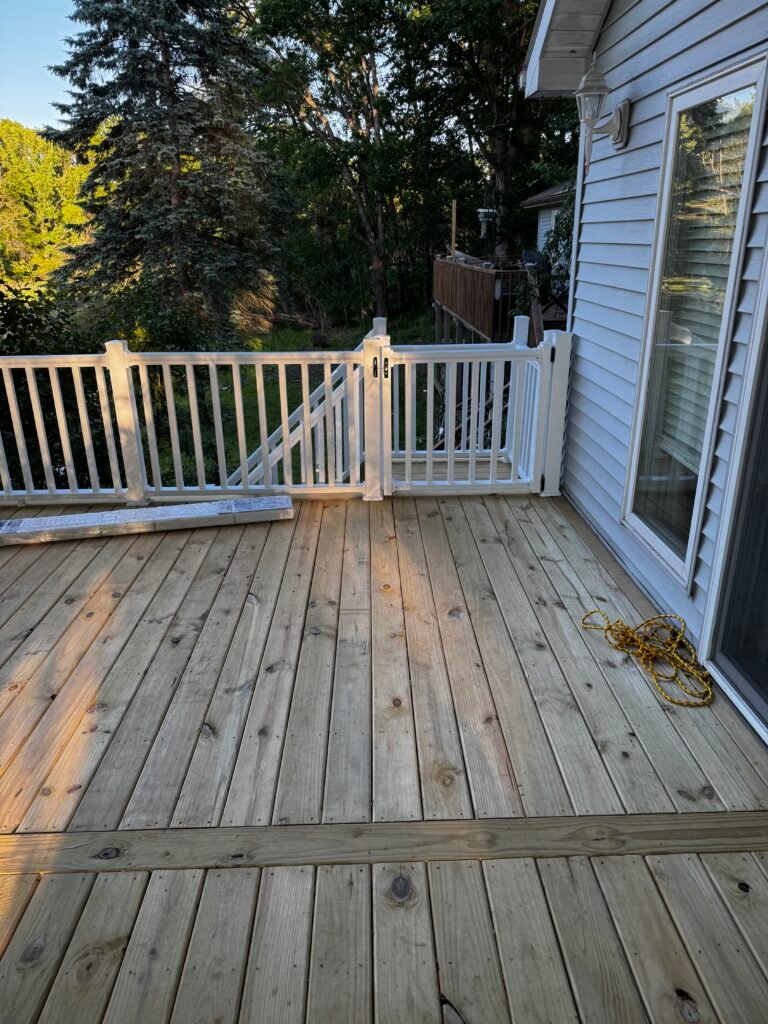 Weathered wood deck fitted with new white vinyl railing and gate