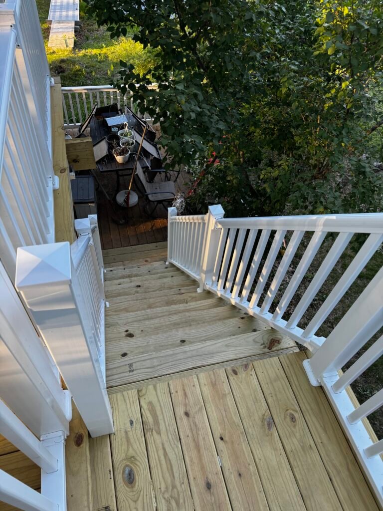 Backyard wood deck and staircase finished with white railing, aerial view
