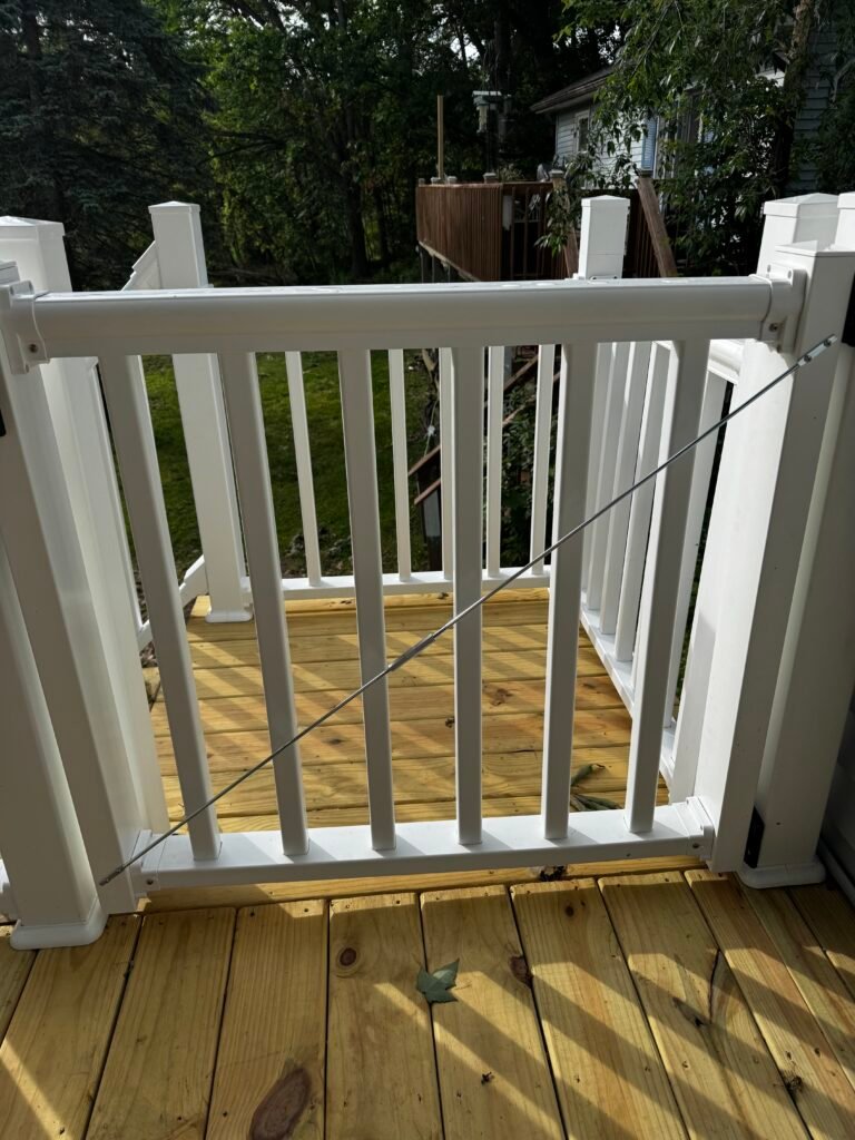 Wood deck fitted with a white vinyl safety gate and railing