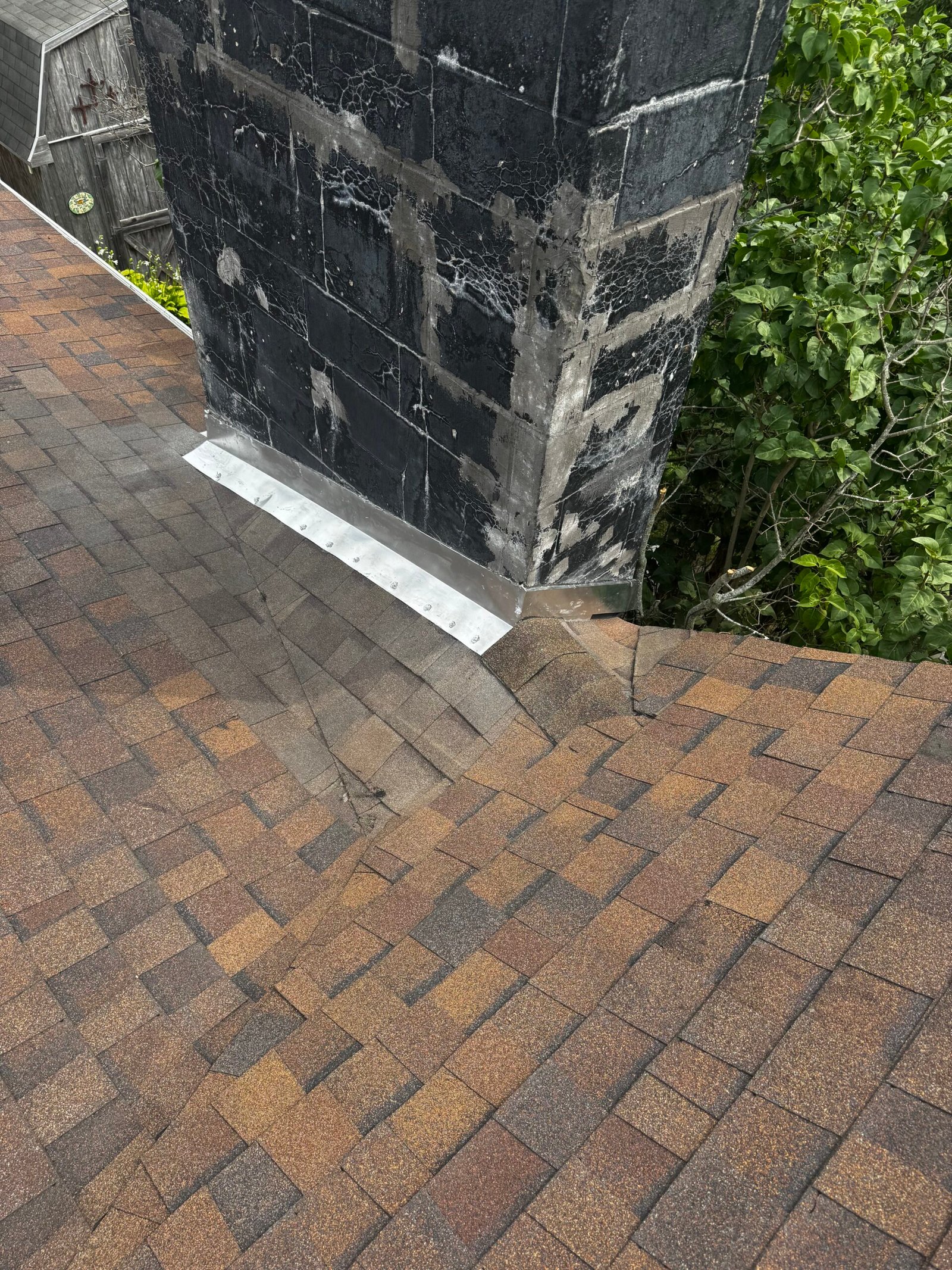 Close-up of chimney base flashing repair on an asphalt shingle roof
