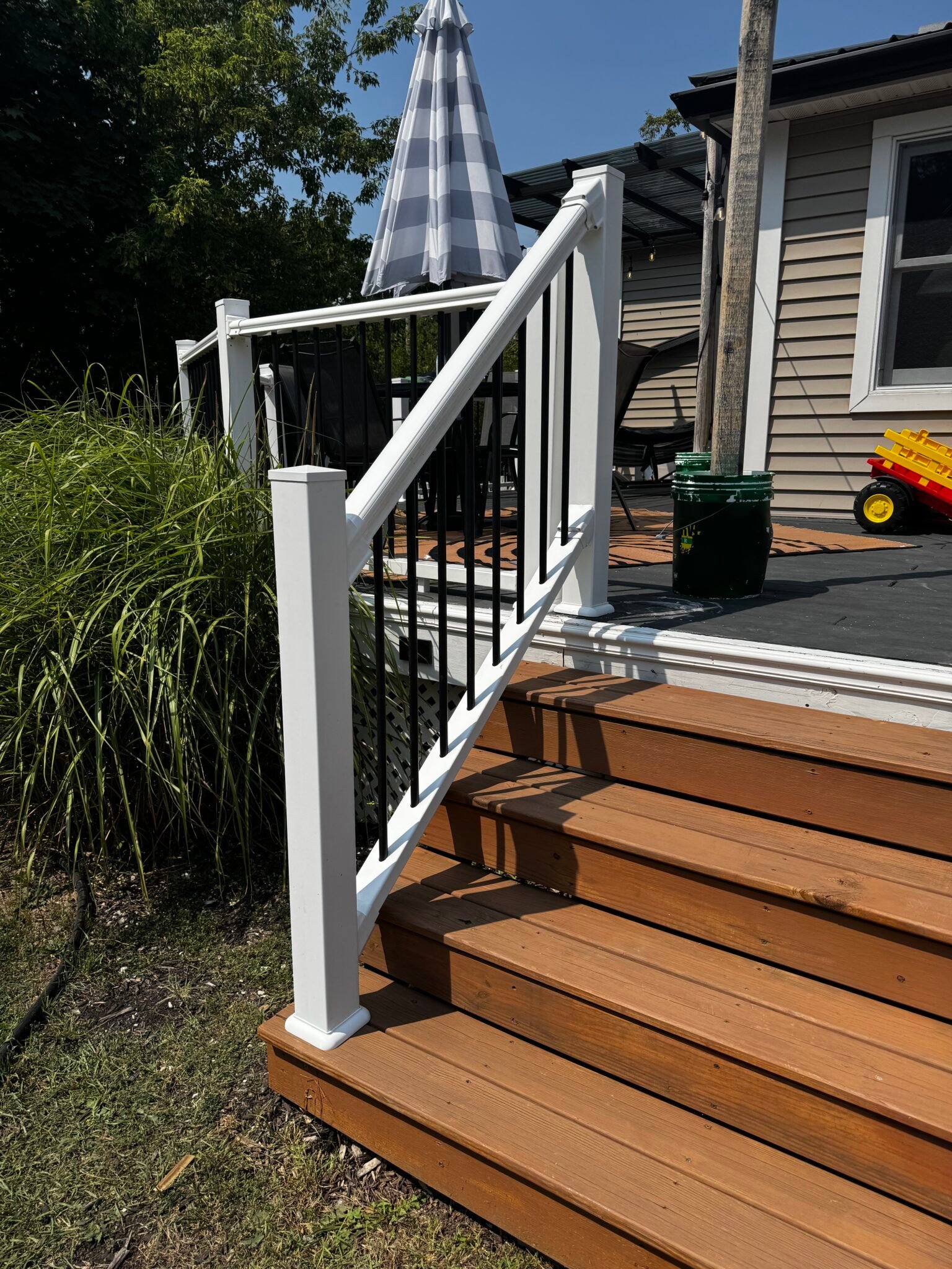 New wood staircase with white metal railing leading to a backyard deck