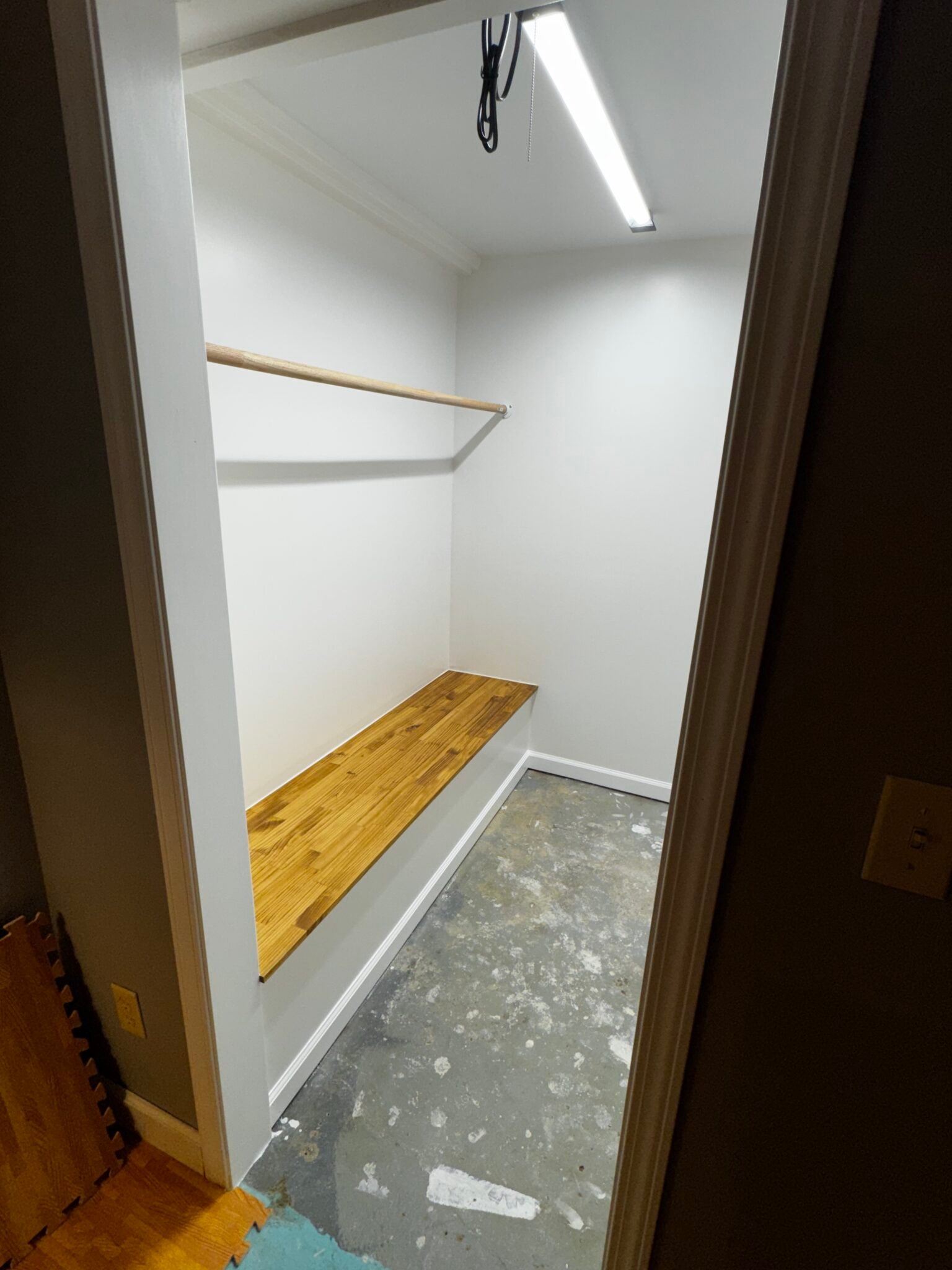 Custom wood bench and shelving installed in a mudroom closet