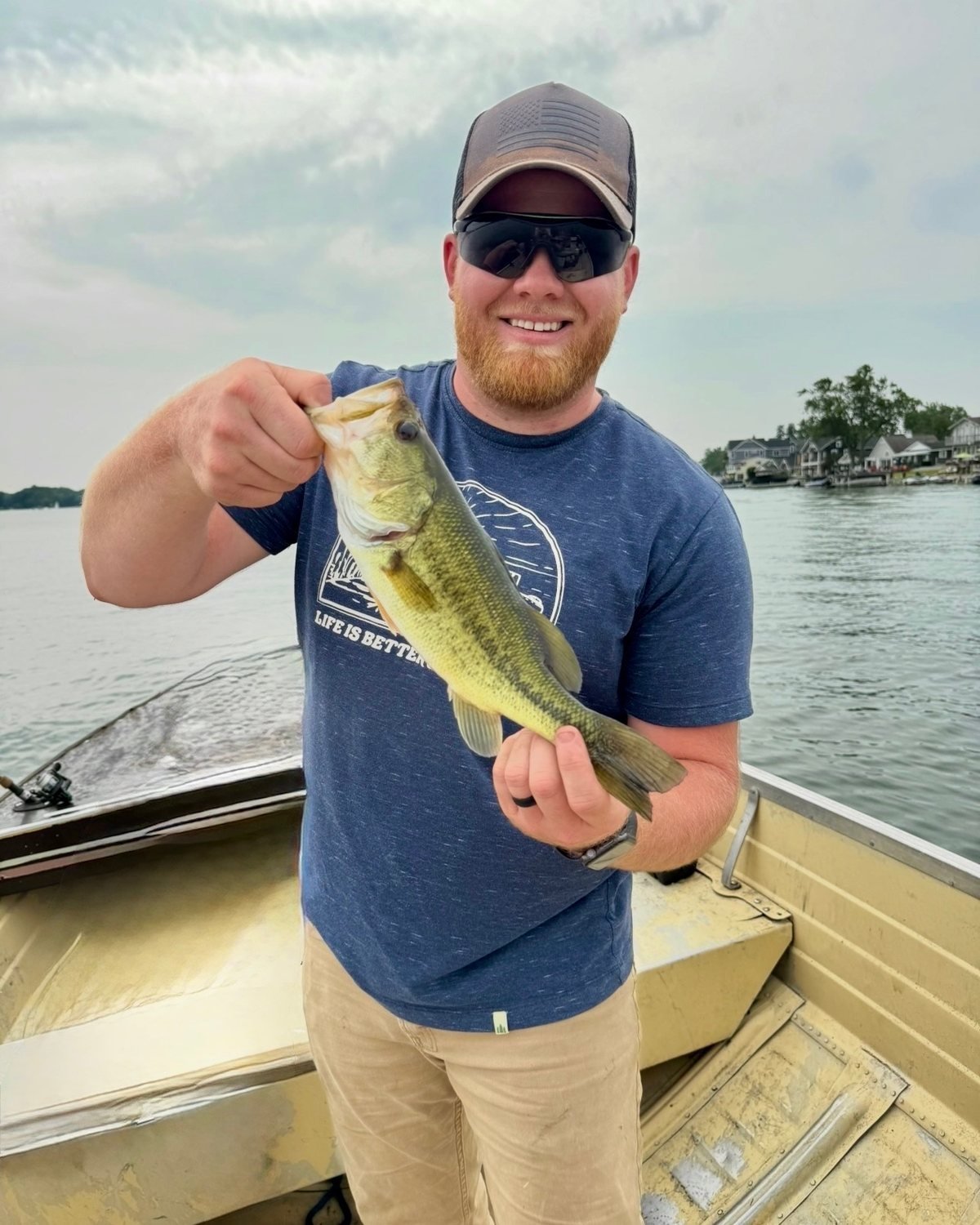 Jacob LaLonde, owner of True North Home Services, smiling on a boat with a largemouth bass